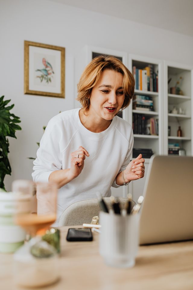 Joyful woman having an engaging video call in her home office setting.
