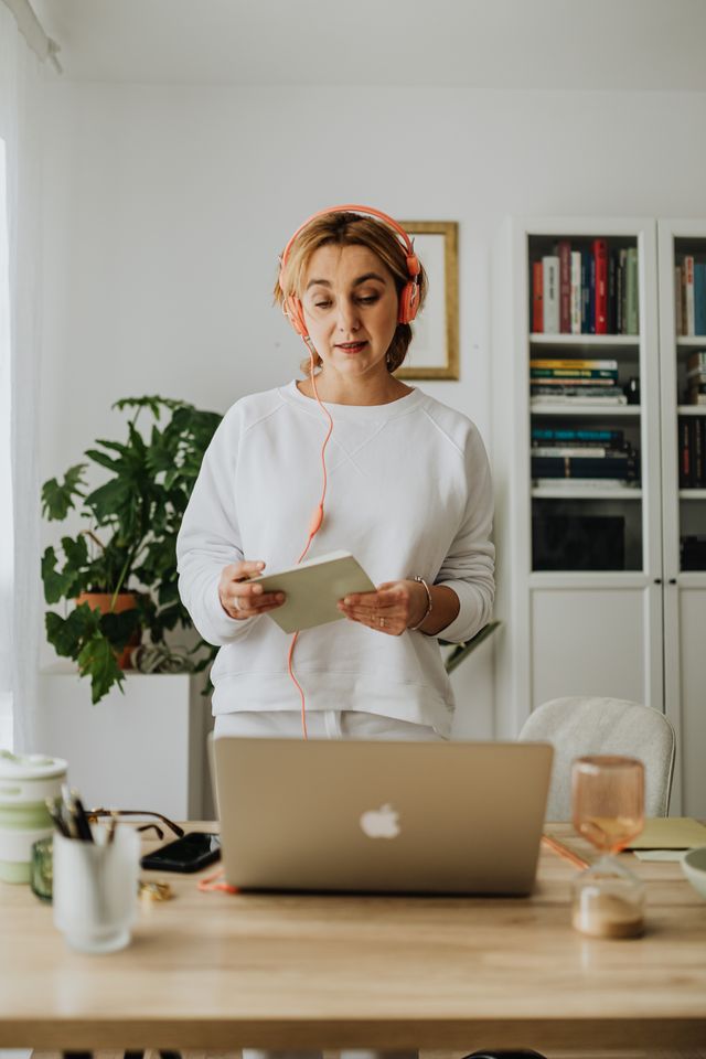 A woman wearing headphones leads an online webinar from her home office.